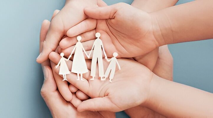 Hands holding a paper cut-out of a family representing mental health support and care