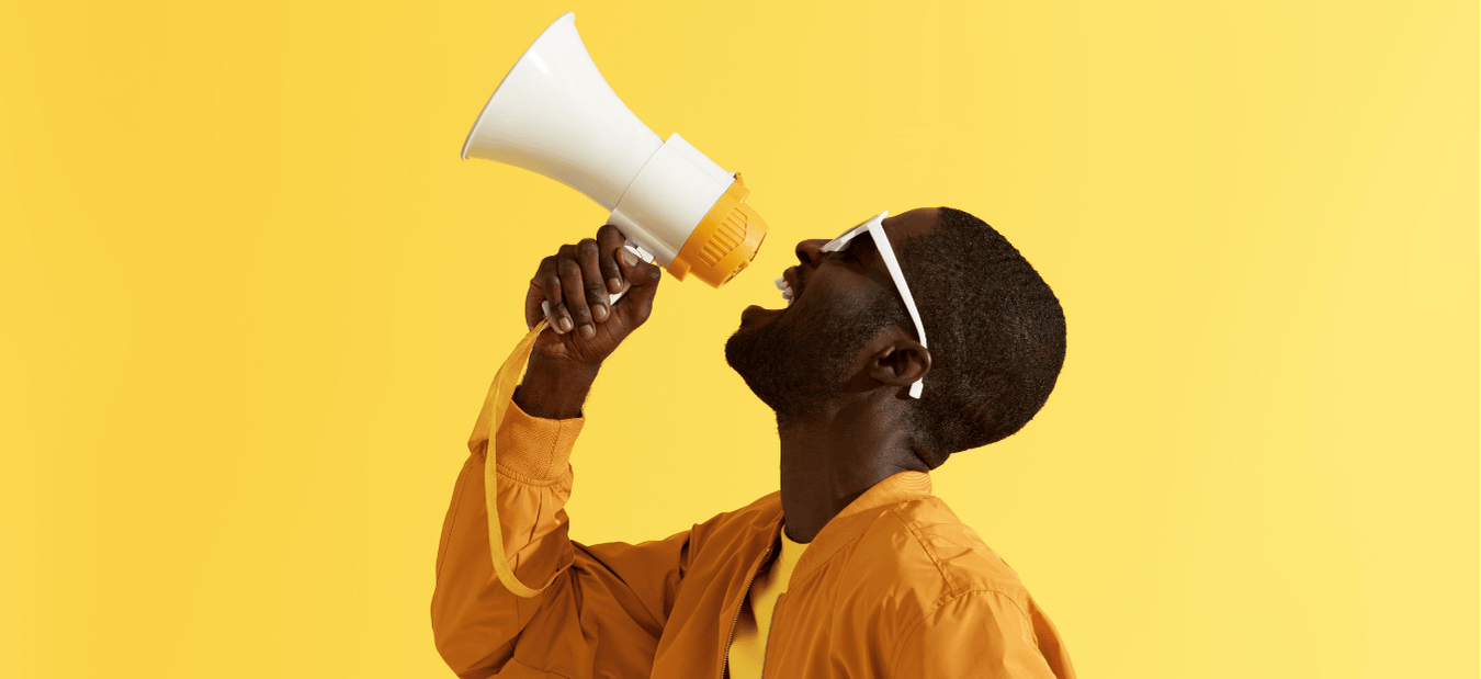 Man in sunglasses shouting into a megaphone against a bright yellow background