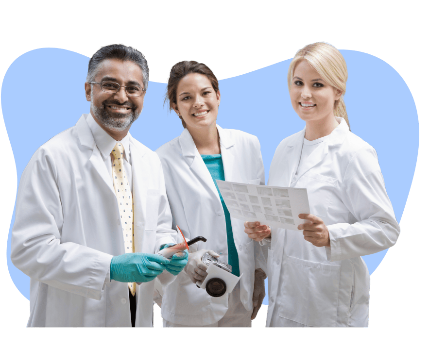 Three dental professionals smiling and posing together in lab coats, showcasing a collaborative and diverse dental care team.